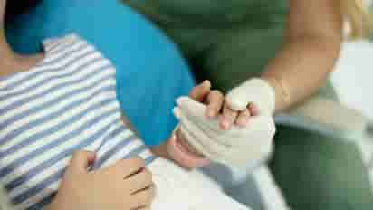 A dentist holds a young patient's hand during a dental emergency appointment